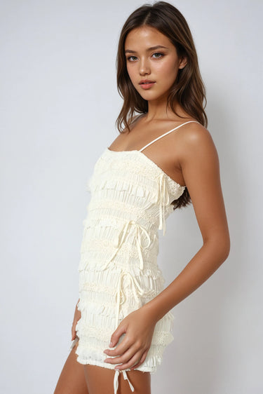 Textured knit romper with smocking, adjustable straps, and side ties. Light, breezy, and softly powerful.